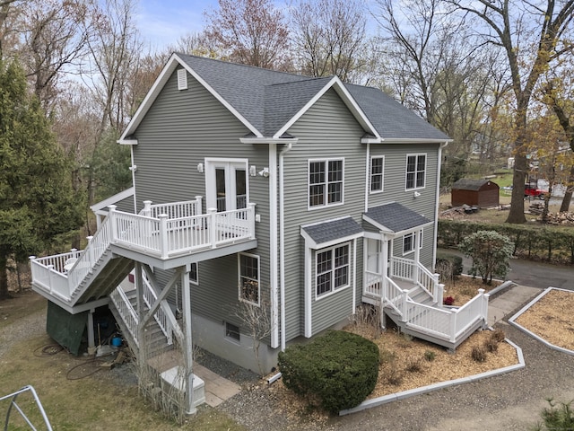 back of house with stairway, roof with shingles, and a wooden deck