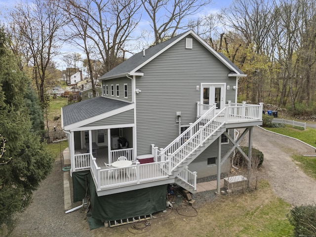 back of property with a deck, stairway, and a shingled roof