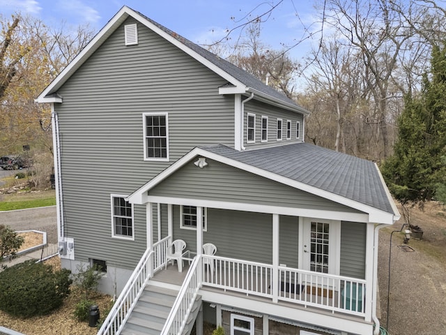 rear view of property with a porch and a shingled roof