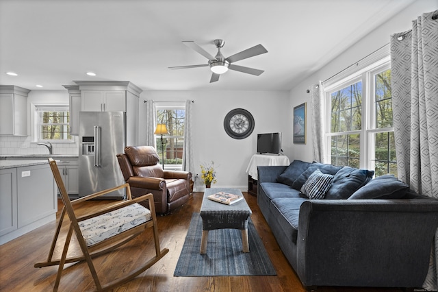 living area featuring healthy amount of natural light, dark wood finished floors, a ceiling fan, and recessed lighting