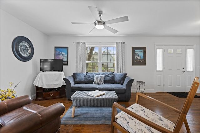 living area featuring baseboards, a ceiling fan, and dark wood-type flooring