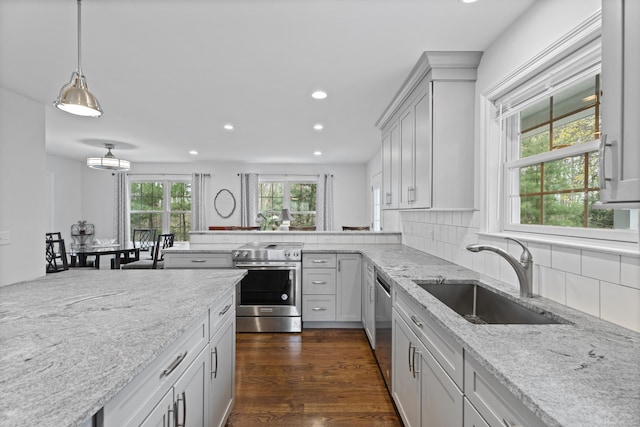 kitchen with stainless steel appliances, a sink, recessed lighting, tasteful backsplash, and light stone countertops