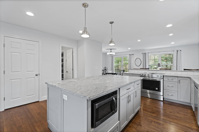 kitchen with stainless steel appliances, a kitchen island, recessed lighting, light stone countertops, and dark wood-style floors