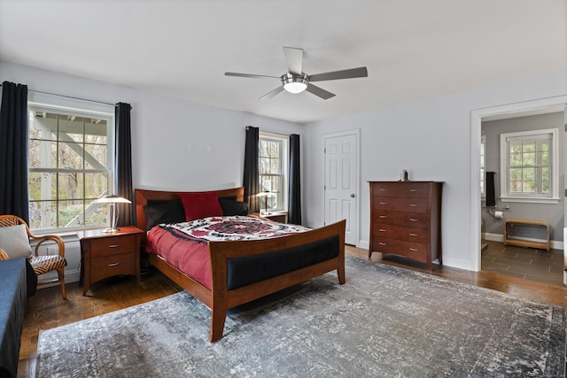 bedroom featuring wood finished floors, a ceiling fan, ensuite bathroom, and baseboards