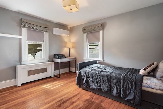 43 Bibbins Ave, Fairfield, CT 06825 - bedroom featuring baseboards, a wall unit AC, light wood finished floors, and radiator