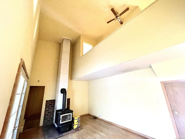 6 Stirling Ct, Middletown, CT 06457 - unfurnished living room with a wood stove, a high ceiling, ceiling fan, and wood finished floors
