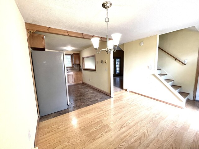 6 Stirling Ct, Middletown, CT 06457 - kitchen with light wood-style floors, a notable chandelier, pendant lighting, a textured ceiling, and freestanding refrigerator