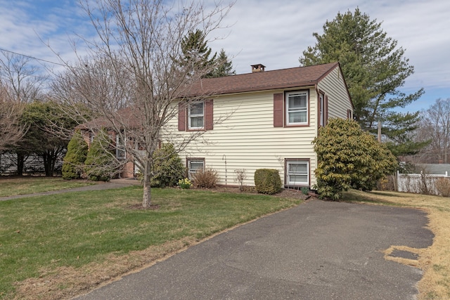 view of side of home featuring a lawn, fence, and a chimney