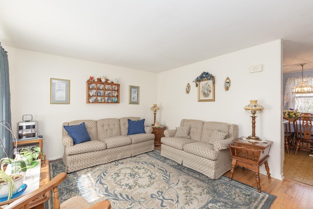 living room with baseboards, a notable chandelier, and wood finished floors