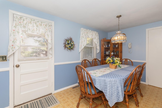 dining space featuring light floors, visible vents, baseboards, and a chandelier