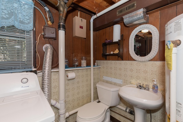 half bath with washer / clothes dryer, visible vents, tile walls, a sink, and toilet