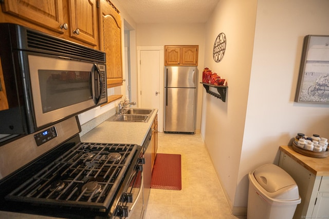 30 Merrimac St, Watertown, CT 06779 - kitchen with brown cabinetry, appliances with stainless steel finishes, light countertops, a sink, and a textured ceiling