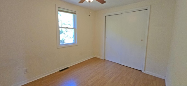 unfurnished bedroom with a closet, ceiling fan, light wood finished floors, baseboards, and visible vents
