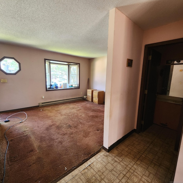 carpeted spare room featuring a baseboard heating unit, a textured ceiling, and baseboards