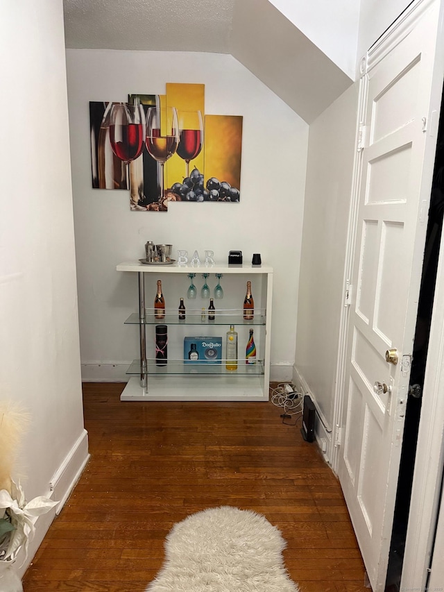 interior space featuring wood finished floors, vaulted ceiling, and baseboards