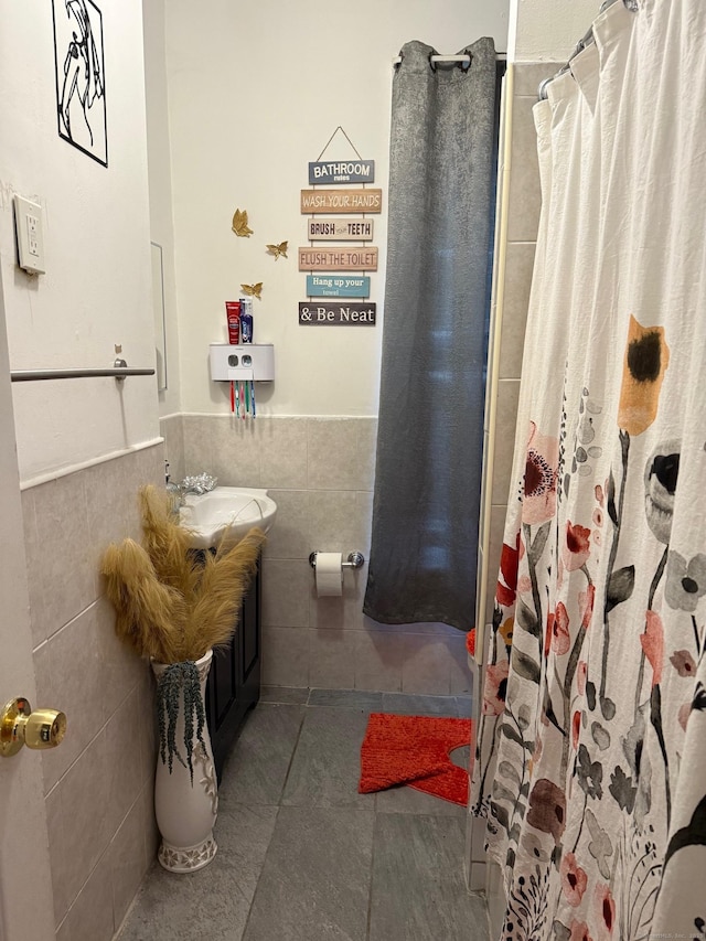 bathroom with tile walls, wainscoting, a shower with shower curtain, and tile patterned flooring