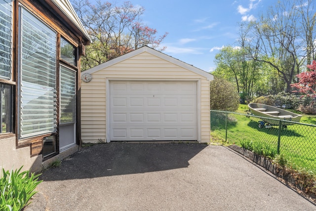 detached garage featuring fence and aphalt driveway