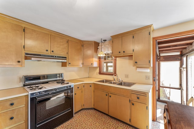 kitchen with under cabinet range hood, range with gas stovetop, a sink, and light countertops
