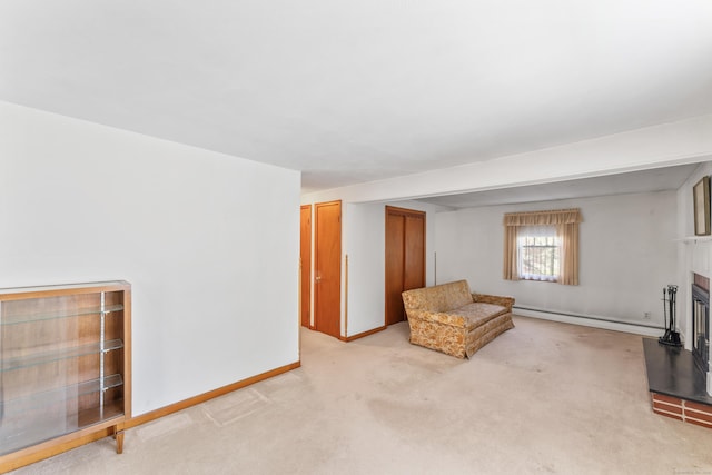 unfurnished room with a fireplace with raised hearth, baseboards, a baseboard heating unit, and light colored carpet