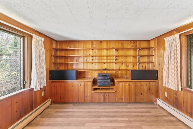 unfurnished living room featuring wood walls, built in features, wood finished floors, and baseboard heating