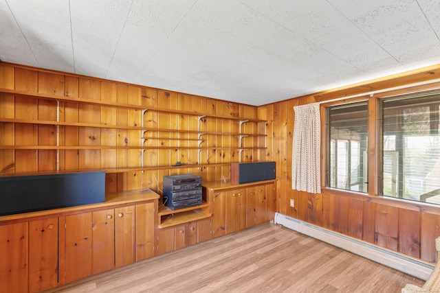 unfurnished living room with a baseboard radiator, light wood-style flooring, and wooden walls