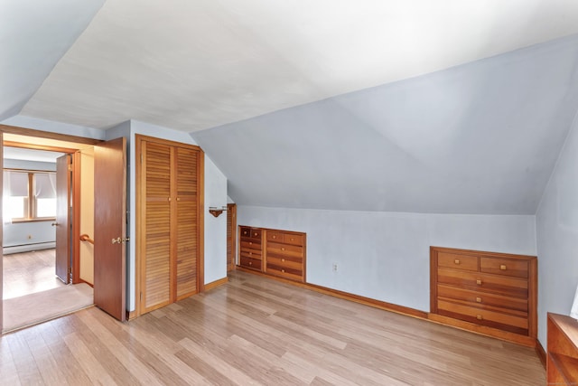 additional living space with baseboards, light wood-style flooring, lofted ceiling, and a baseboard radiator