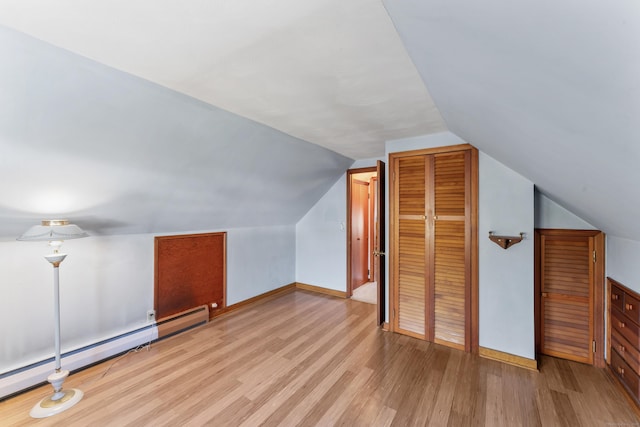 additional living space featuring a baseboard heating unit, vaulted ceiling, and light wood-style floors