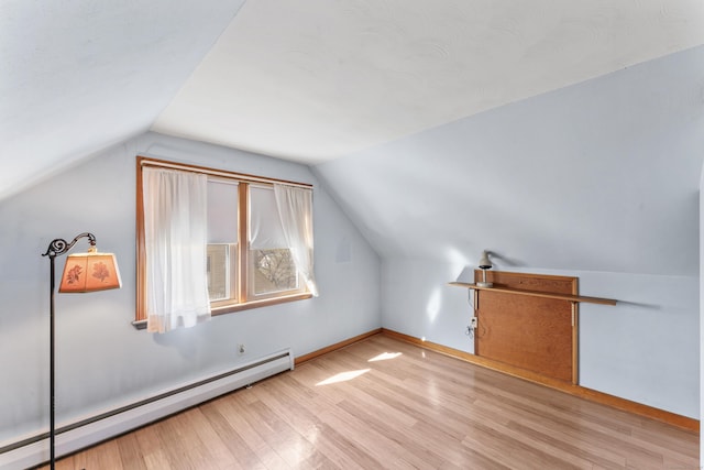 additional living space featuring baseboards, a baseboard heating unit, wood finished floors, and lofted ceiling