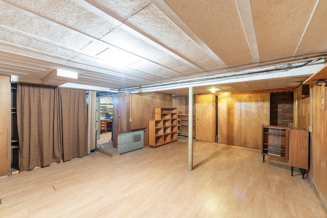 finished basement featuring wood walls, radiator, and wood finished floors