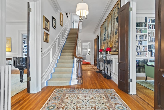 259 N Main St, Stonington, CT 06378 - entrance foyer featuring crown molding, wood finished floors, radiator, stairway, and a decorative wall