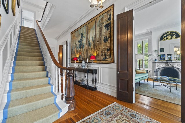 259 N Main St, Stonington, CT 06378 - foyer with crown molding, stairway, wood finished floors, a decorative wall, and a fireplace