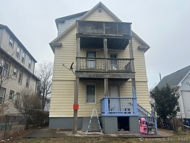 rear view of house featuring a balcony and a porch