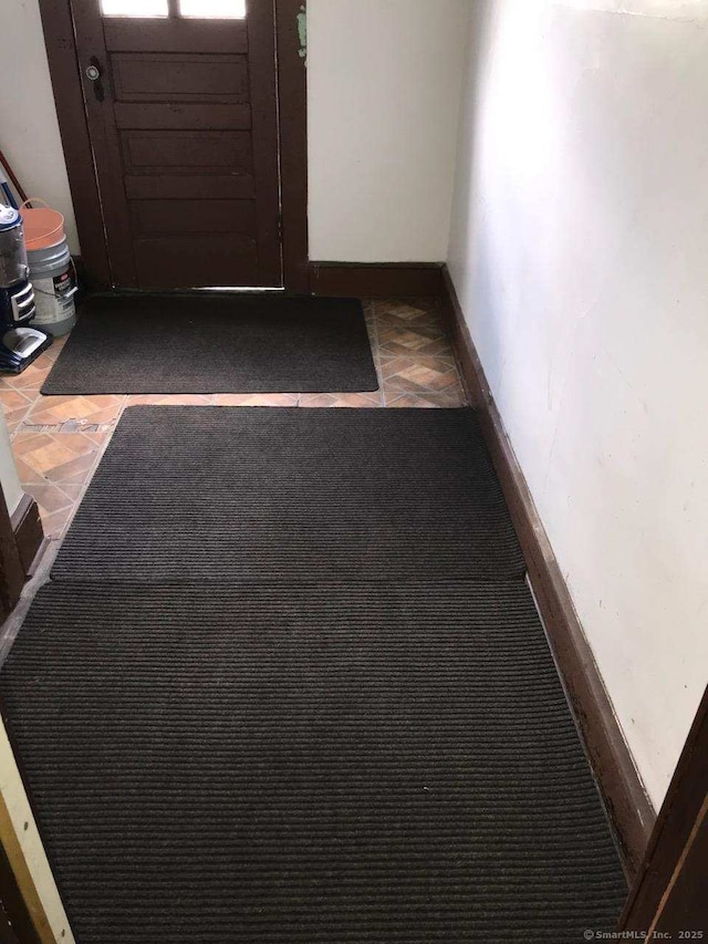 hall featuring tile patterned flooring and baseboards