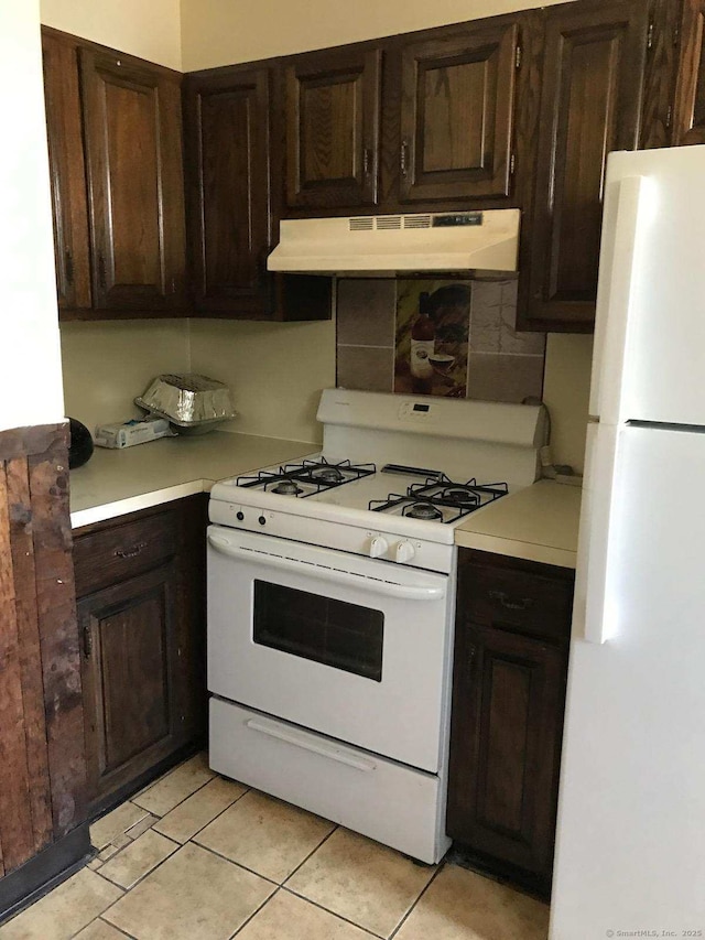 kitchen featuring white appliances, under cabinet range hood, light countertops, and light tile patterned flooring