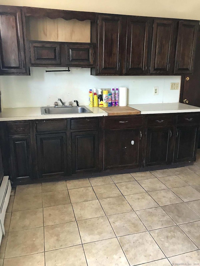 kitchen with a sink, light countertops, light tile patterned flooring, and a baseboard heating unit