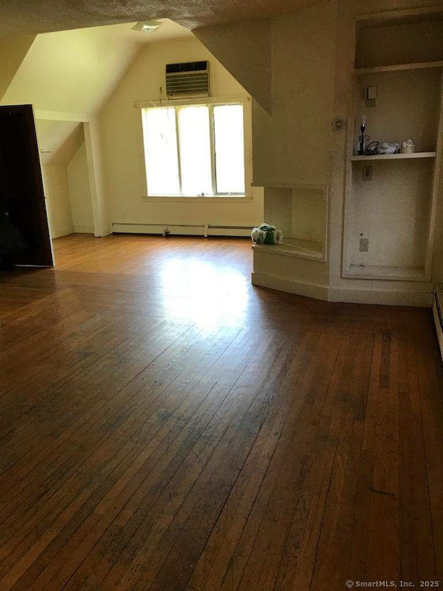 bonus room with hardwood / wood-style floors, a wall mounted AC, lofted ceiling, and baseboard heating