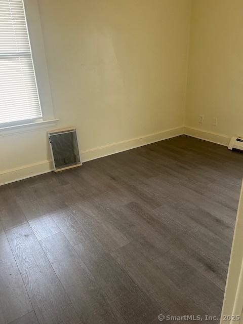 empty room with dark wood-style flooring and baseboards