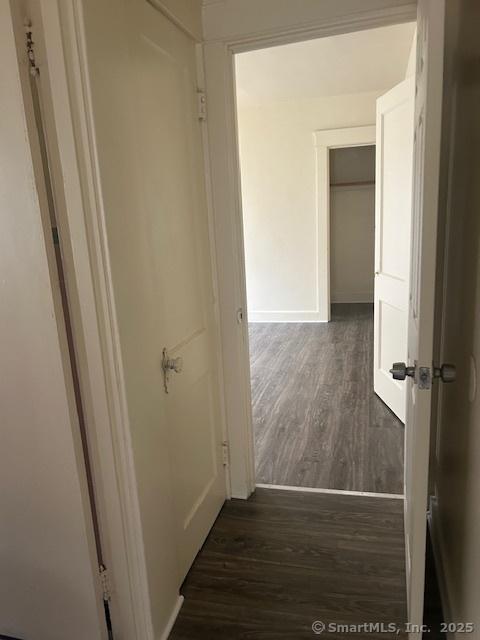 corridor featuring dark wood-style floors and baseboards