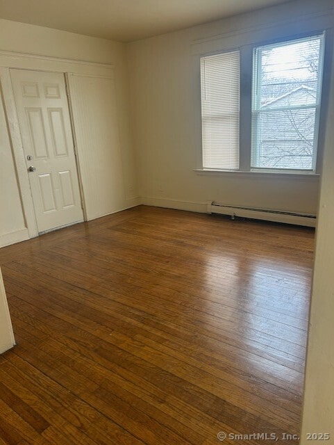 spare room with a baseboard heating unit and hardwood / wood-style floors