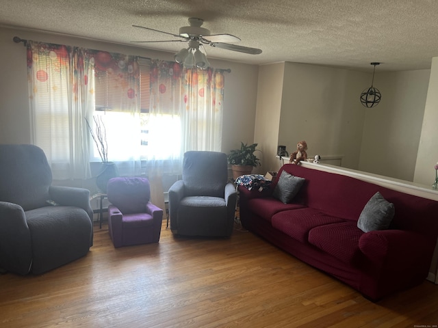living area featuring a textured ceiling, wood finished floors, and ceiling fan