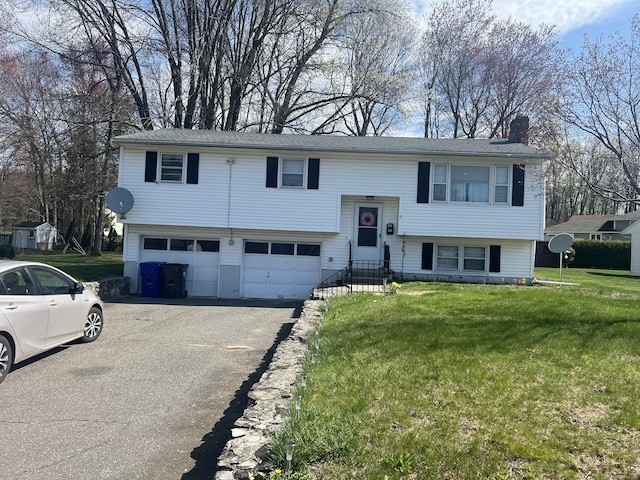 raised ranch with a front lawn, a garage, aphalt driveway, and a chimney