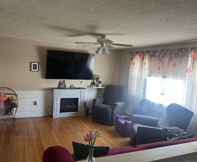living room featuring a textured ceiling, ceiling fan, and wood-type flooring