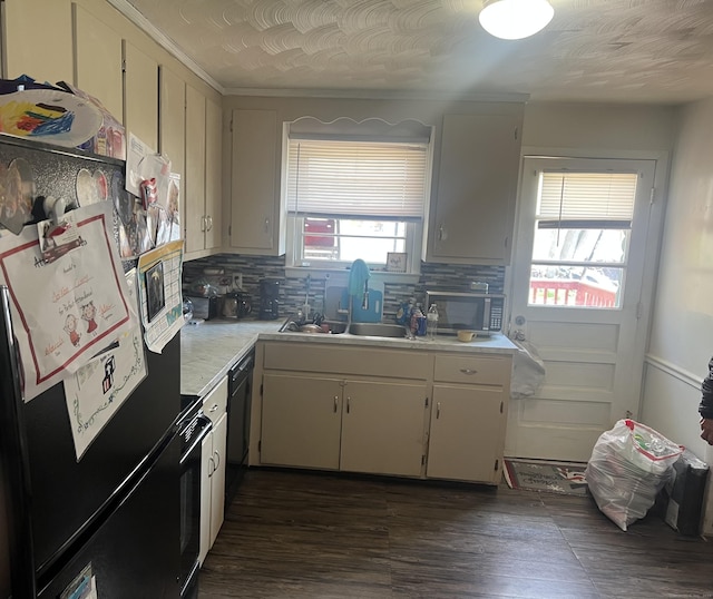 kitchen featuring dark wood-style floors, a sink, tasteful backsplash, black appliances, and light countertops
