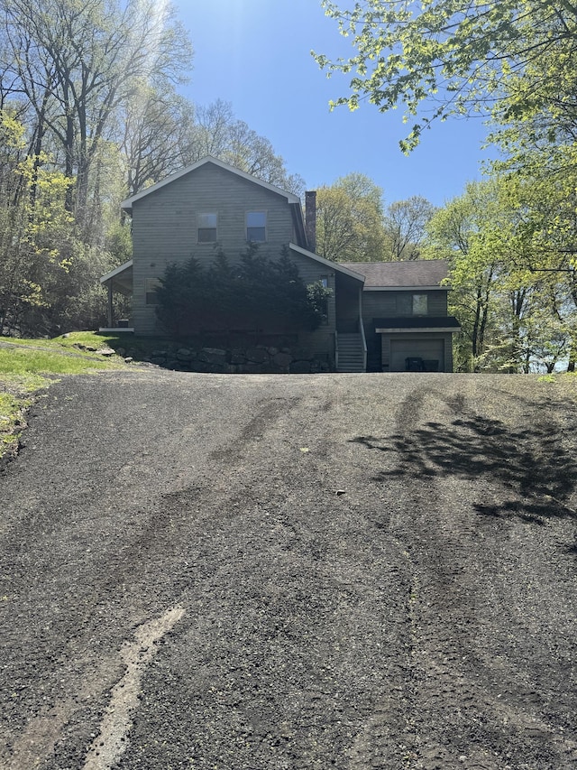 view of home's exterior with driveway, a chimney, and a garage