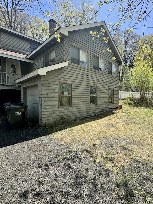 view of side of home with a chimney and driveway