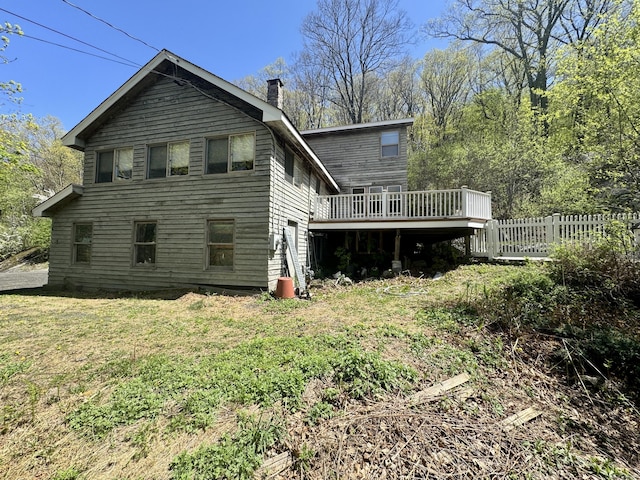 rear view of property with a lawn, a deck, fence, and a chimney