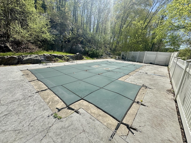 view of swimming pool with fence, a covered pool, and a patio area