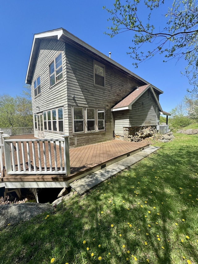 rear view of property featuring central air condition unit, a yard, and a deck