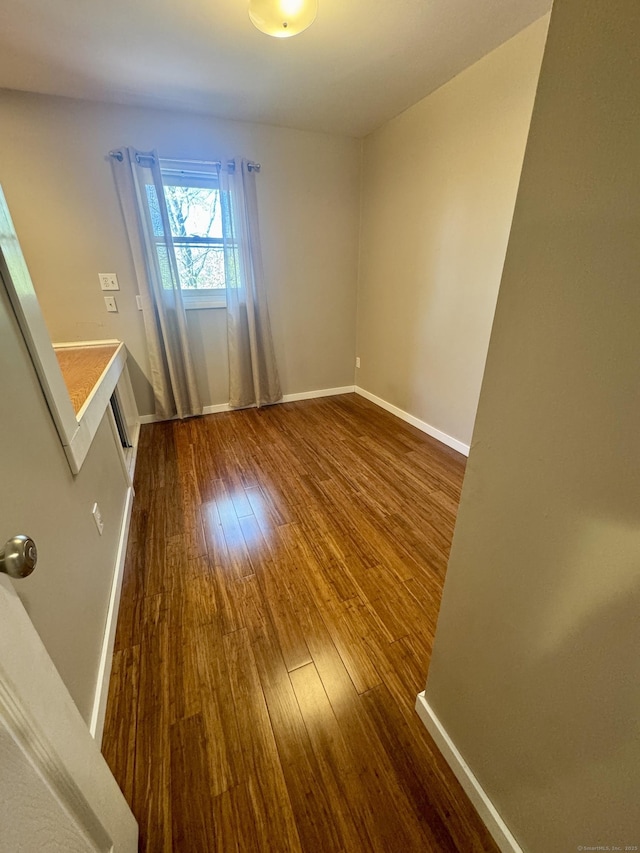 unfurnished room with dark wood-style flooring and baseboards