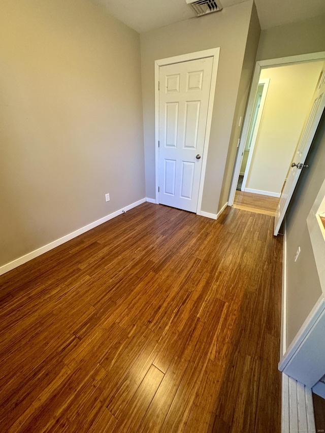 unfurnished bedroom featuring baseboards, wood finished floors, and visible vents